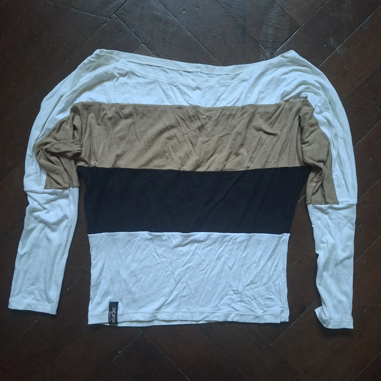 Remera manga larga con cuello bote. Diseño de bloques de color en marrón, negro y blanco.