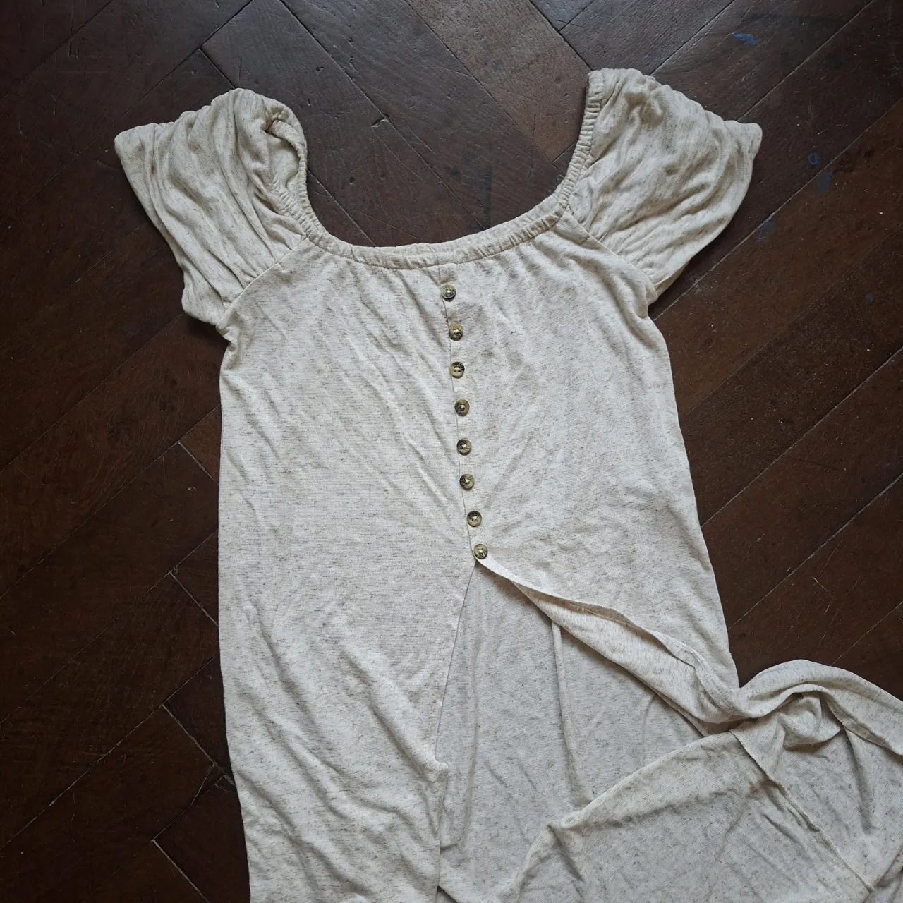 Vestido largo abierto de tela liviana, color crudo con detalles en negro. Posee botones en la parte delantera y tiritas en los hombros.