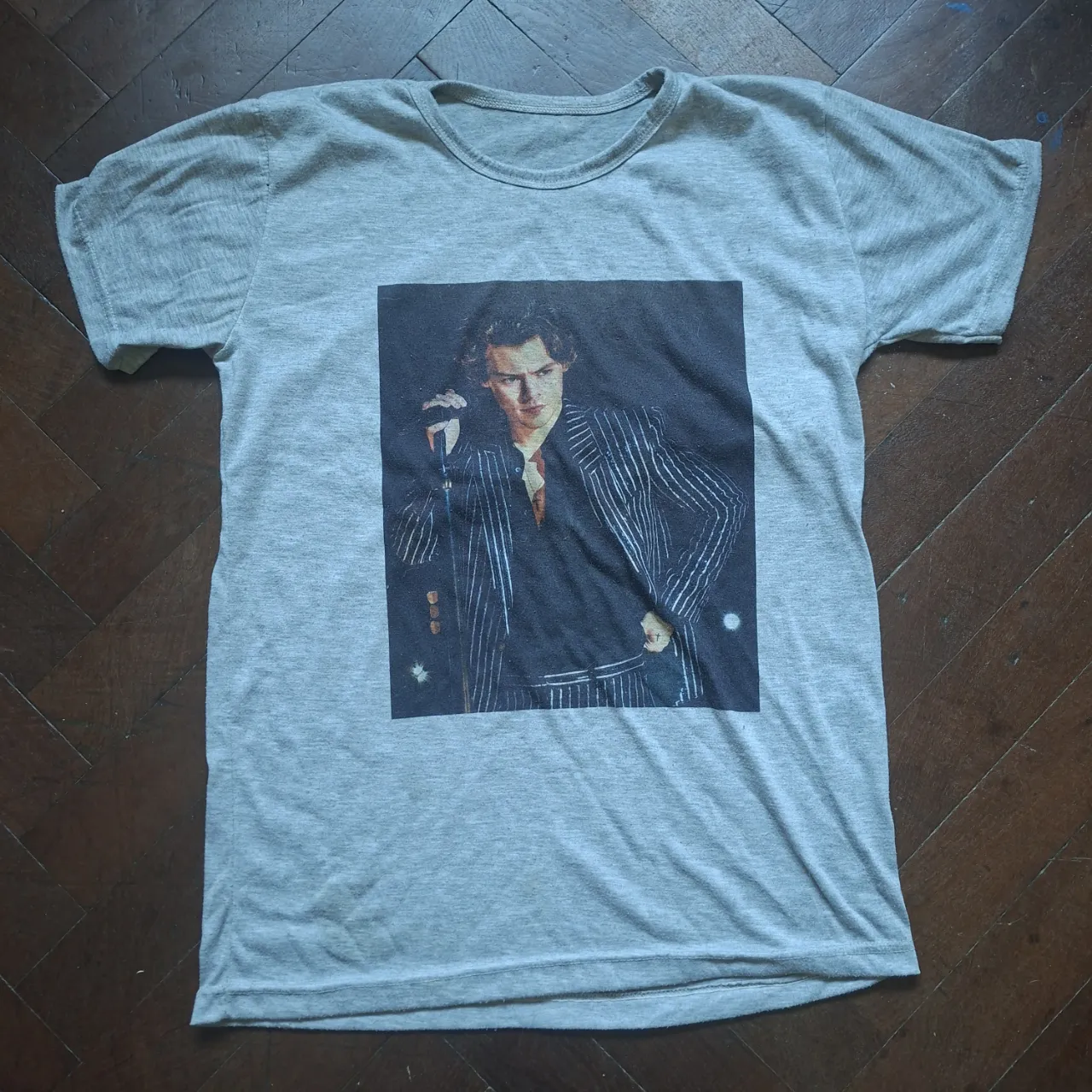 Remera gris de manga corta con estampa de Harry Styles en traje a rayas. Cuello redondo.