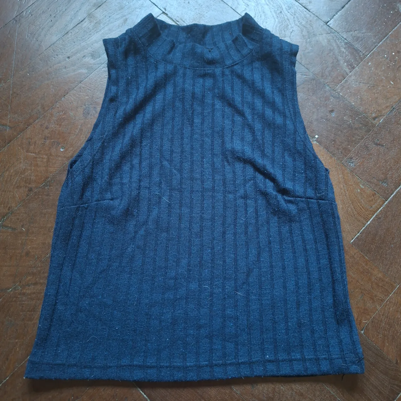 Musculosa azul de tejido acanalado con cuello alto y recorte ovalado en la espalda.