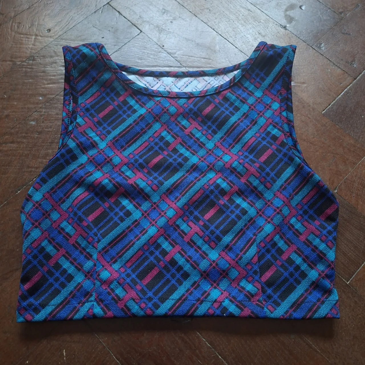Top corto a cuadros en tonos azul, celeste, bordó y negro. Posee recortes en la espalda.