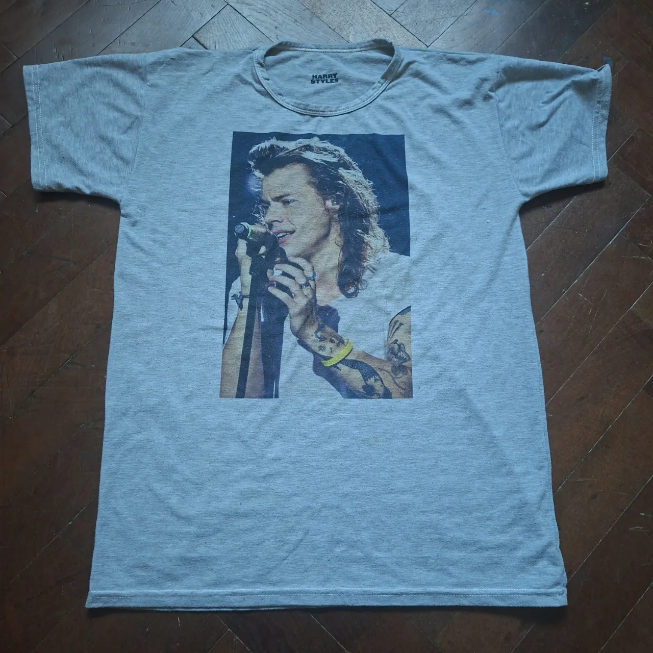 Remera gris de manga corta con estampa de Harry Styles en la parte delantera.