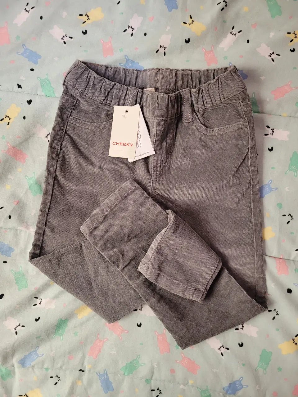 Pantalón de corderoy gris para niño, con etiqueta de la marca Cheeky. Ideal para un look casual y cómodo.