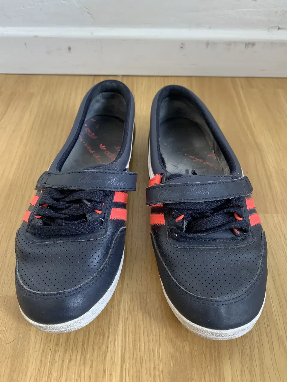 Zapatillas Adidas negras con detalles en rojo, estilo casual con cierre de velcro. Ideales para uso diario.
