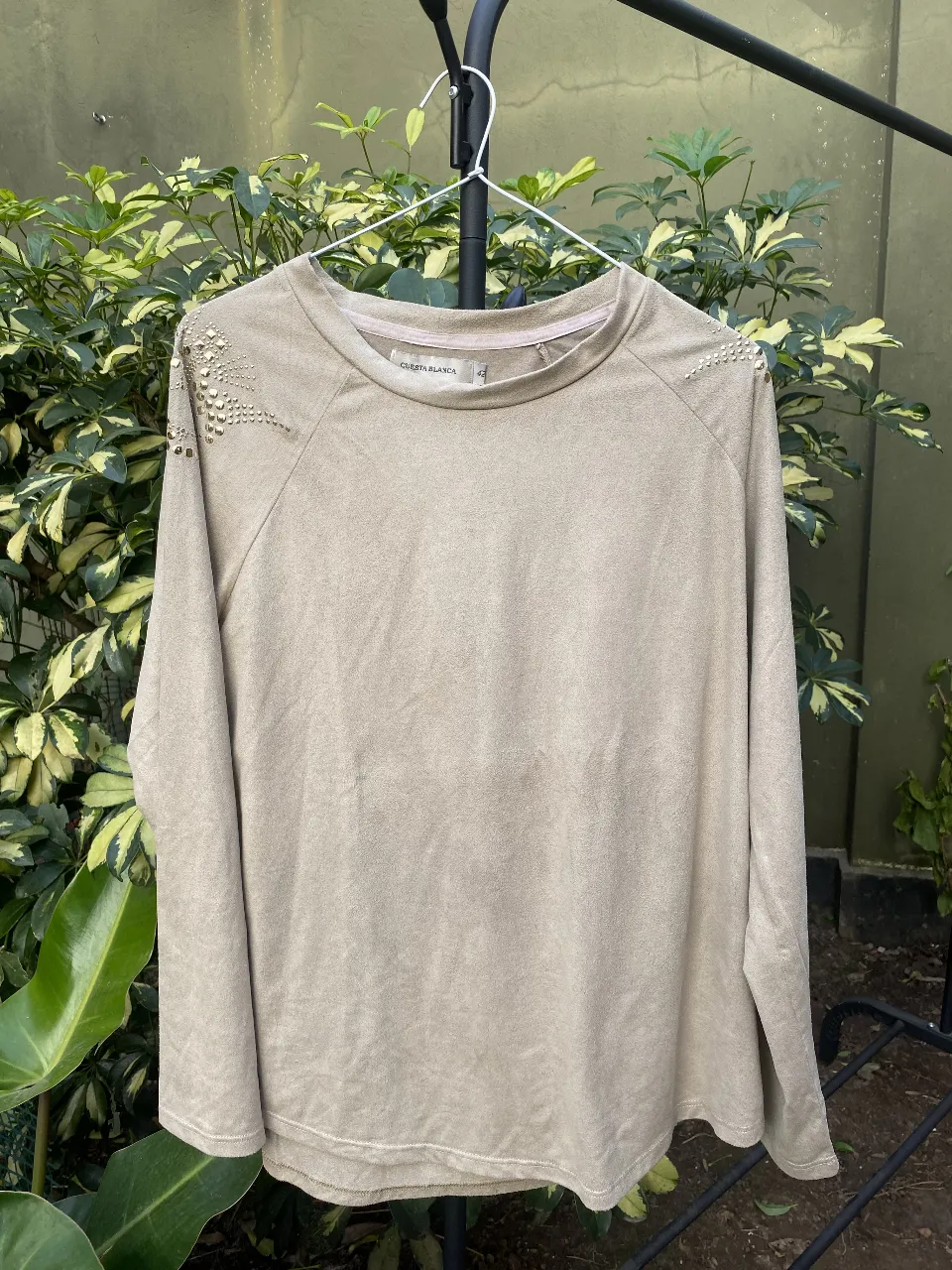 Remera larga de gamuza con detalles dorados en los hombros. Ideal para un look casual y canchero. Perfecto para combinar con jeans o pantalones de vestir.