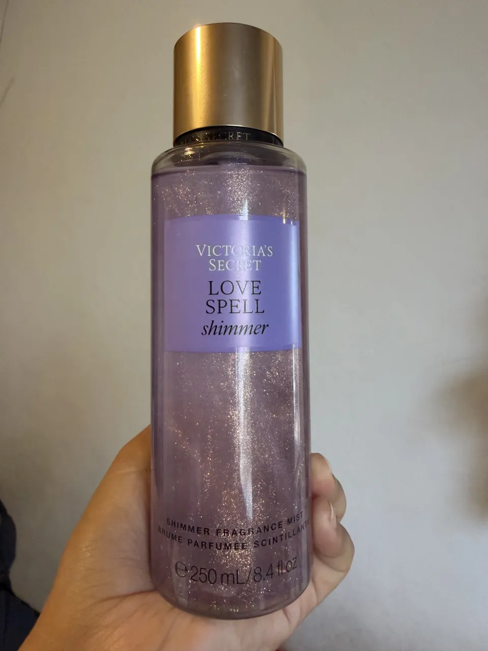 Fragancia corporal Victoria's Secret Love Spell Shimmer. Contiene partículas brillantes para un efecto luminoso. Presentación de 250 ml.