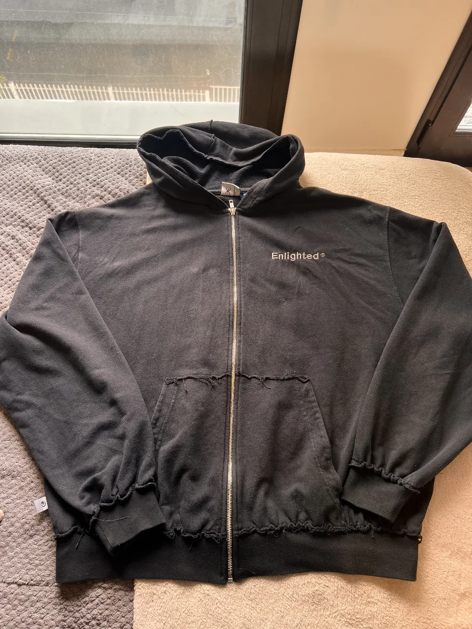 Buzo con cierre negro, con capucha y el logo "Enlighted" estampado en la espalda. Estilo streetwear, ideal para un look casual y cómodo.
Algodón rústico.