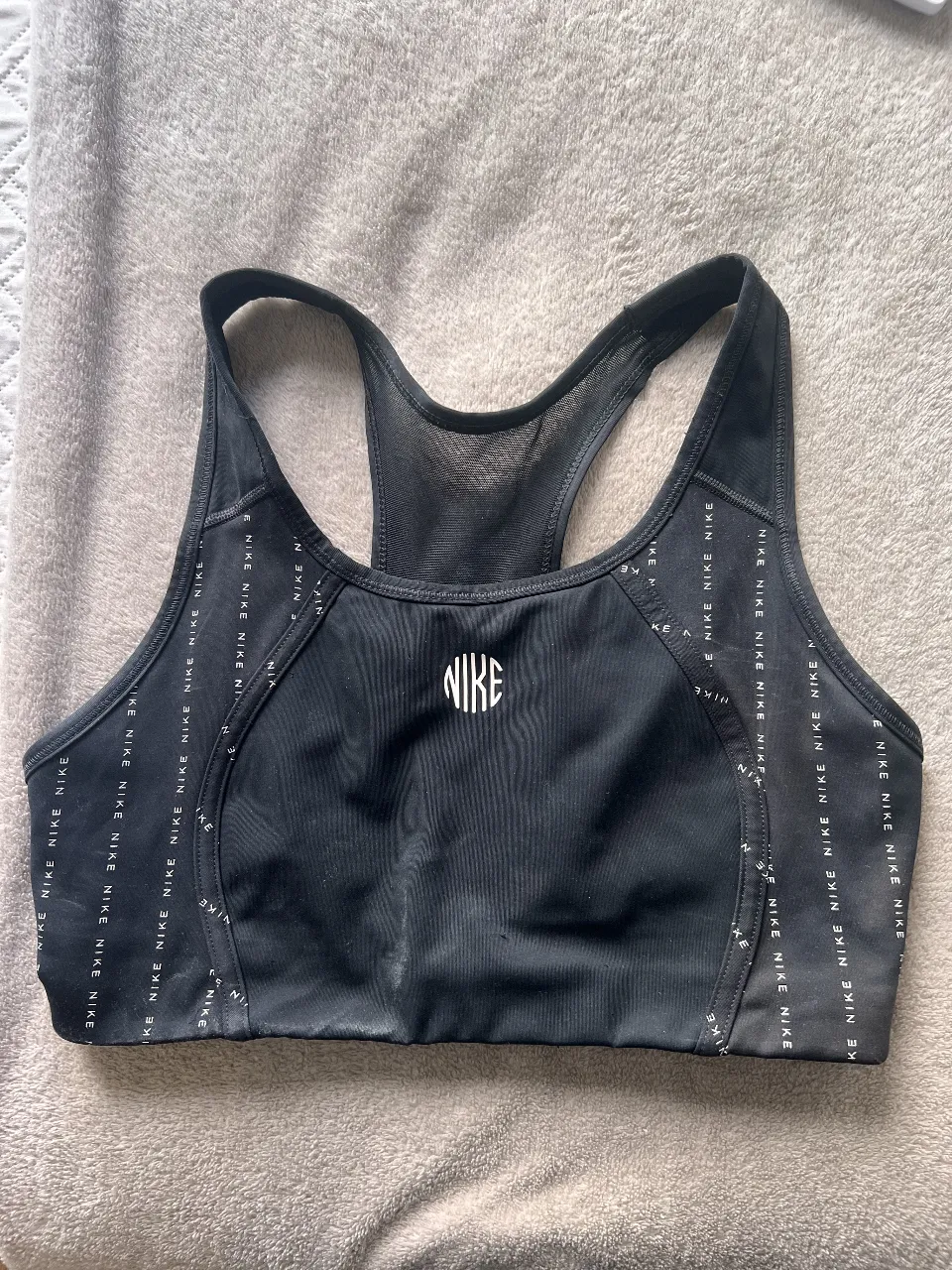 Top deportivo Nike negro con logo blanco. Ideal para entrenamientos de alto impacto. Diseño moderno y ajuste perfecto.