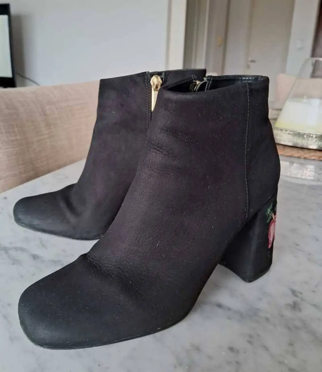 Botines negros de gamuza con detalle floral bordado en el taco. Cierre dorado en el lateral. Medidas. plantilla 25cm, alto taco 8,5cm, alto caña 10 cm. 