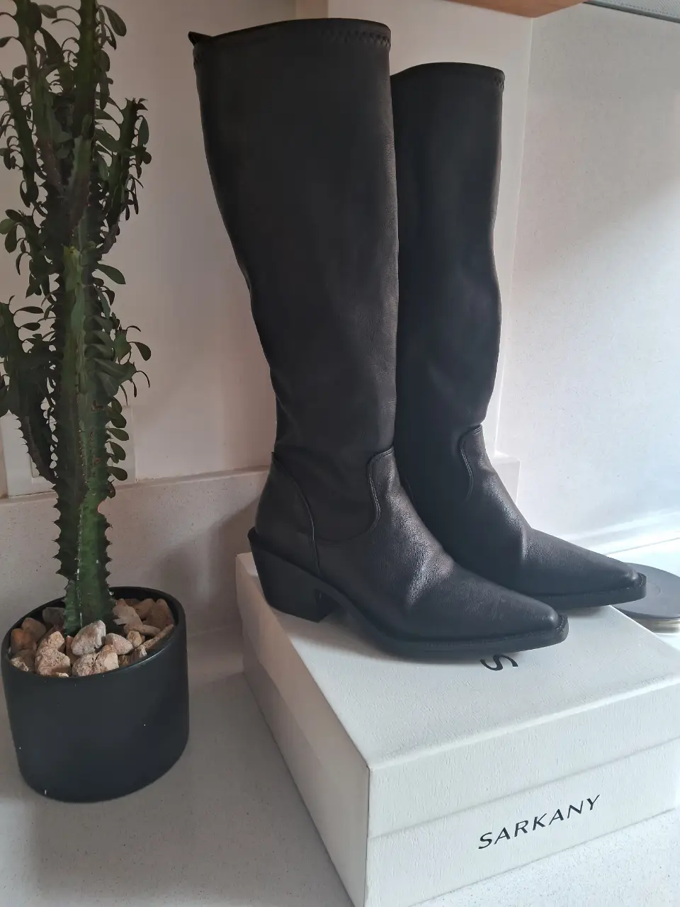 Botas altas negras de cuero sintético, con punta fina y taco bajo. Ideales para un look moderno y elegante. Marca Ricky Sarkany. Medidas: plantilla 25 cm, altura caña 32cm, altura taco 6cm. base y taco de goma. Super cómodas. 