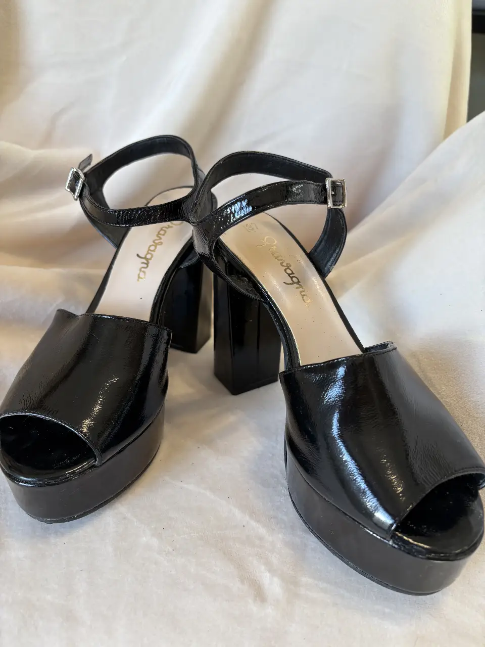Sandalias negras de plataforma con taco ancho y pulsera al tobillo. Diseño charolado, ideales para un look de fiesta o salida.
