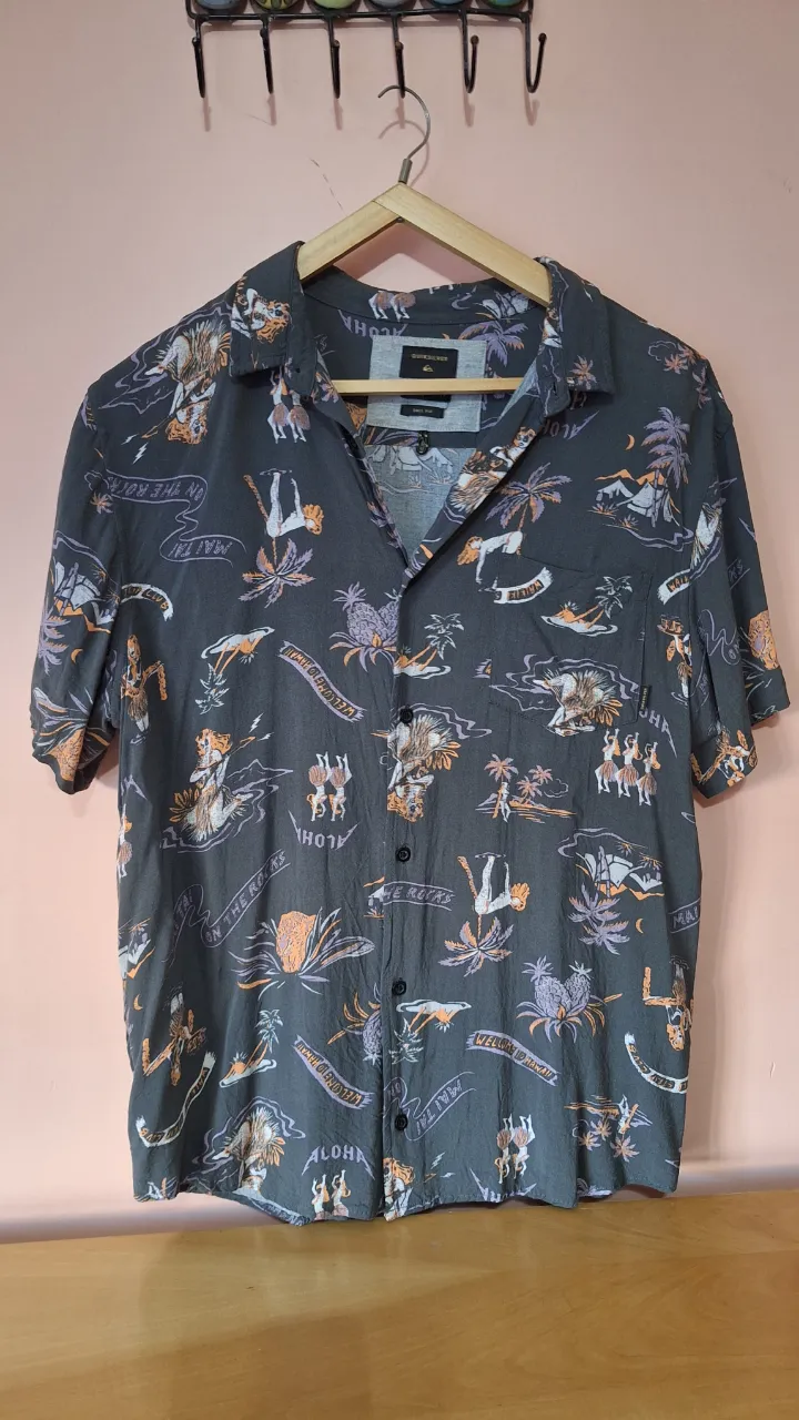 Camisa estampada de manga corta con motivos playeros y de surf. Cuello camisero y botones al frente.