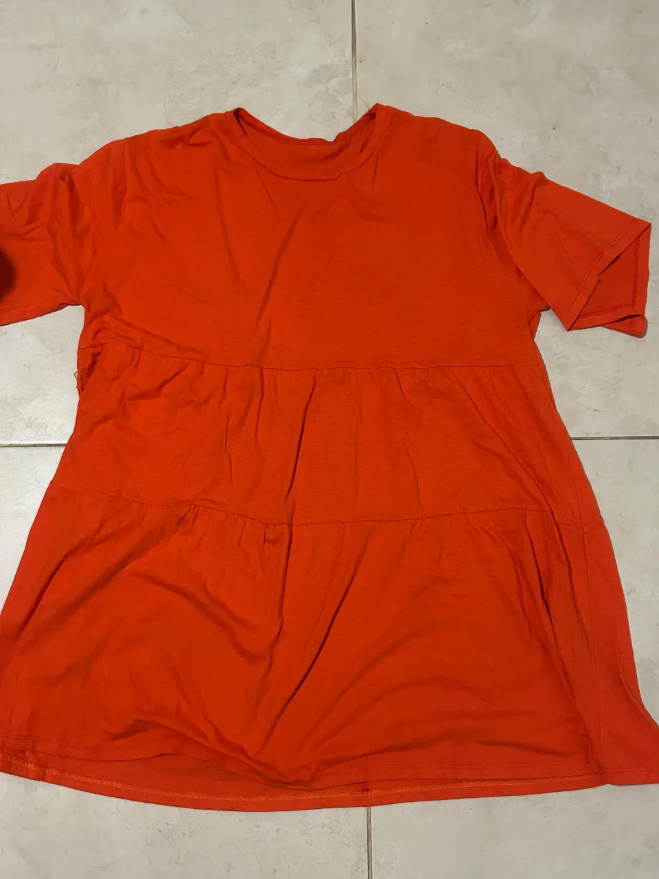 Remera naranja con mangas cortas y corte evasé. Tiene dos fruncidos que le dan un estilo canchero y cómodo. Ideal para el día a día.