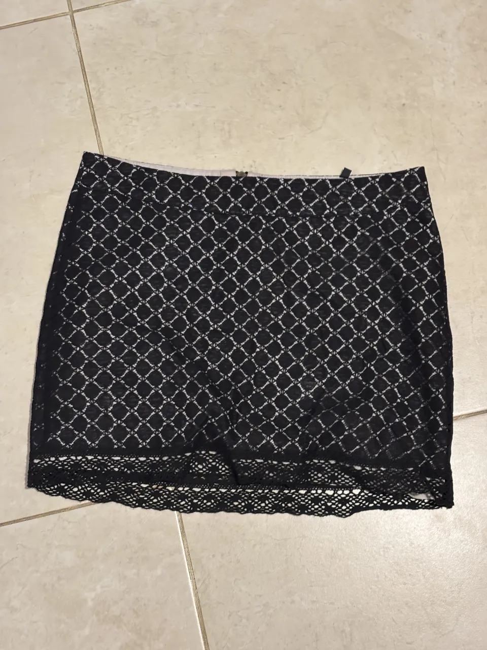 Pollera negra de encaje con detalles en la cintura y terminación. Ideal para un look elegante y sofisticado.