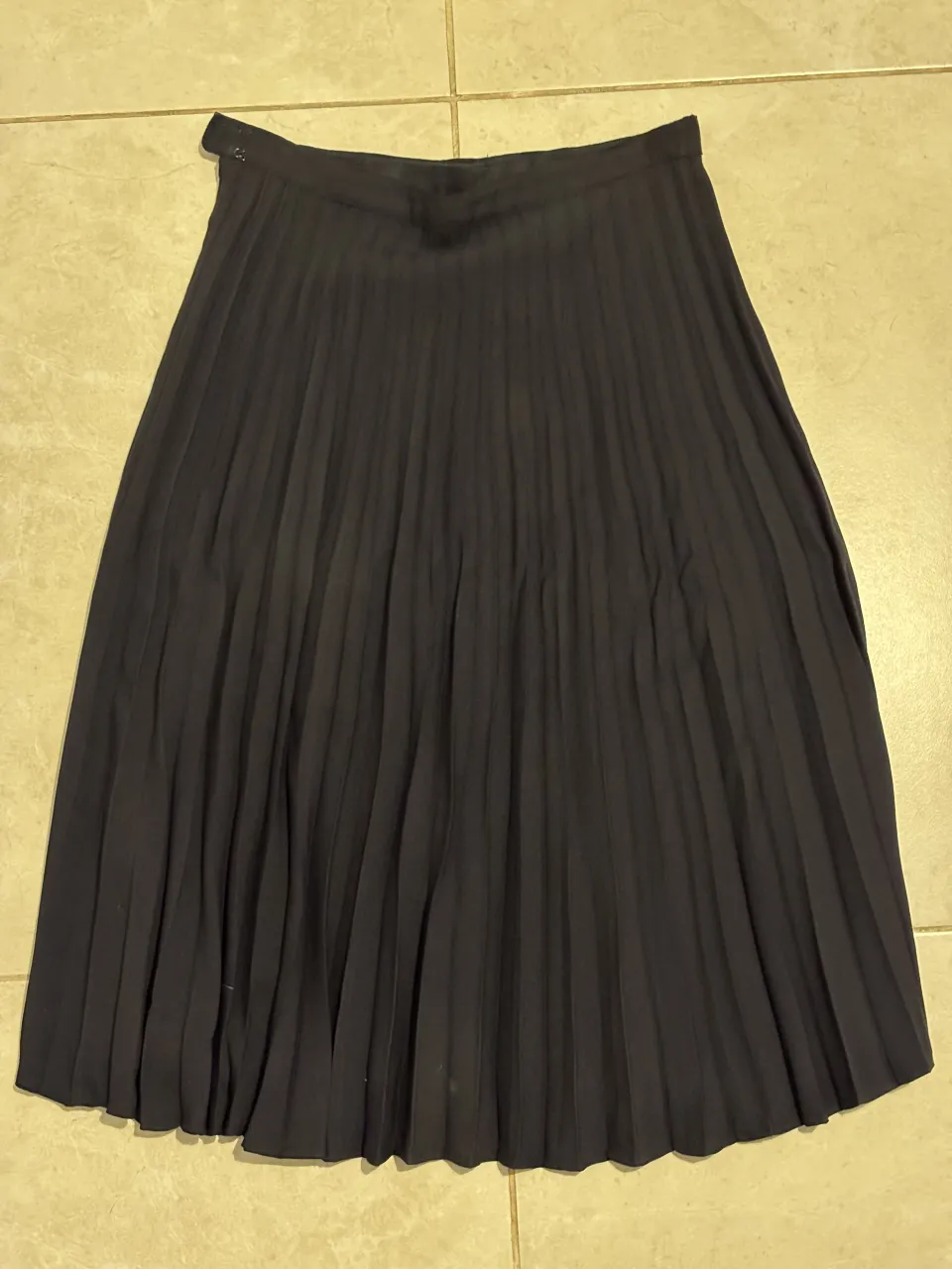 Pollera negra de tiro alto con tablas. Ideal para un look elegante o casual.