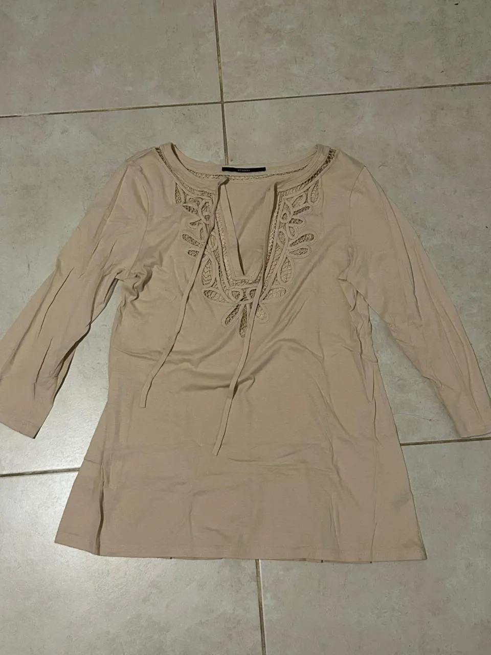 Remera manga larga color tiza con detalles bordados y cordones en el escote. Ideal para un look casual y cómodo.