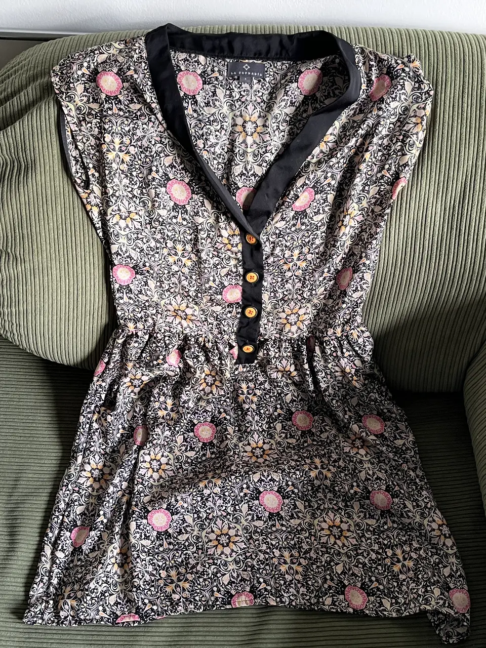 Vestido mini de mujer con estampado floral en tonos negro, rosa y blanco. Cuello con detalle en negro y botones decorativos. 