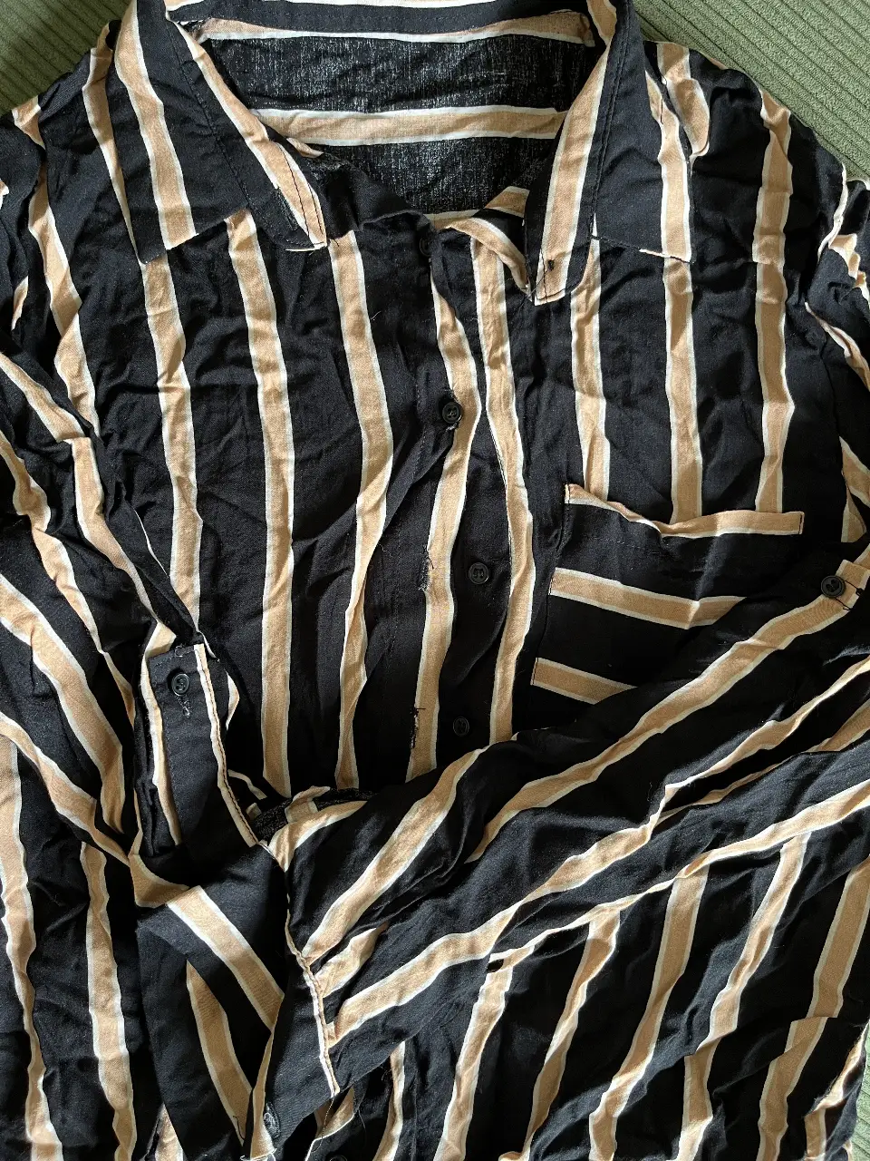 Camisa a rayas verticales en negro y crudo, con bolsillo en el pecho. Ideal para un look casual y moderno.