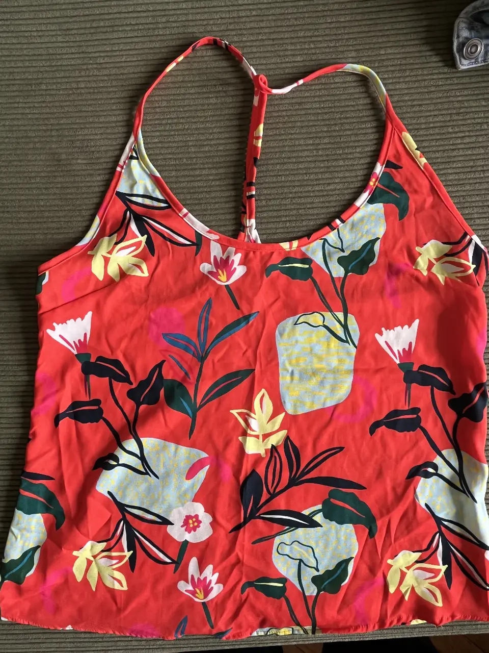 Musculosa de mujer con estampado floral en tonos rojos, amarillos, blancos y azules. Diseño con tirantes finos y espalda descubierta. 