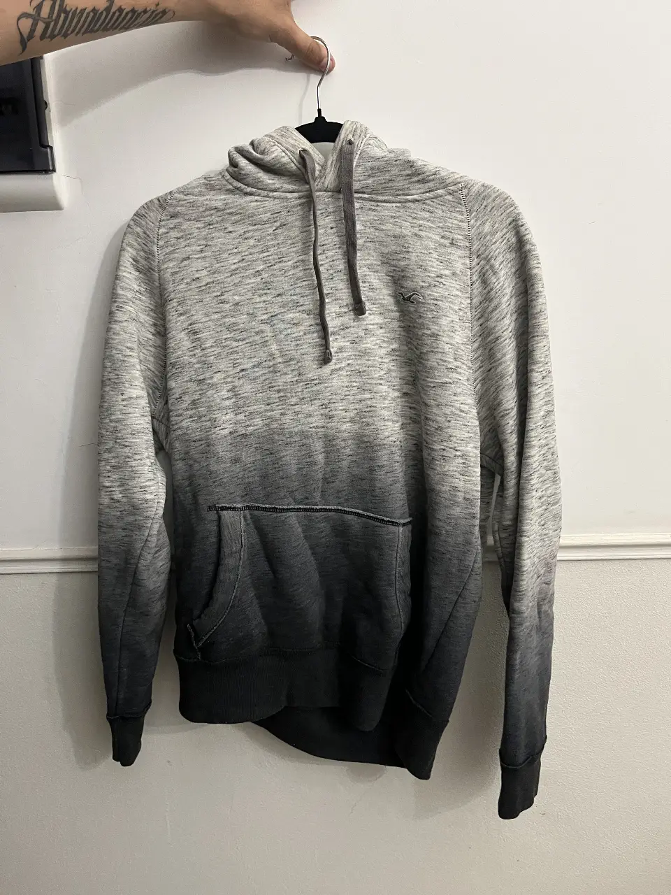 Buzo canguro con capucha para hombre, con diseño degradado en tonos grises y negro. Ideal para un look casual y cómodo.