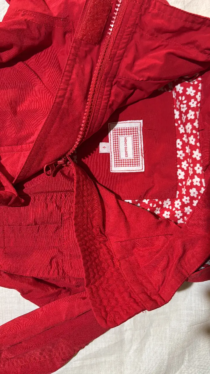 Campera roja para niña, con capucha y cinturón para ajustar en la cintura. Ideal para proteger del frío con estilo.