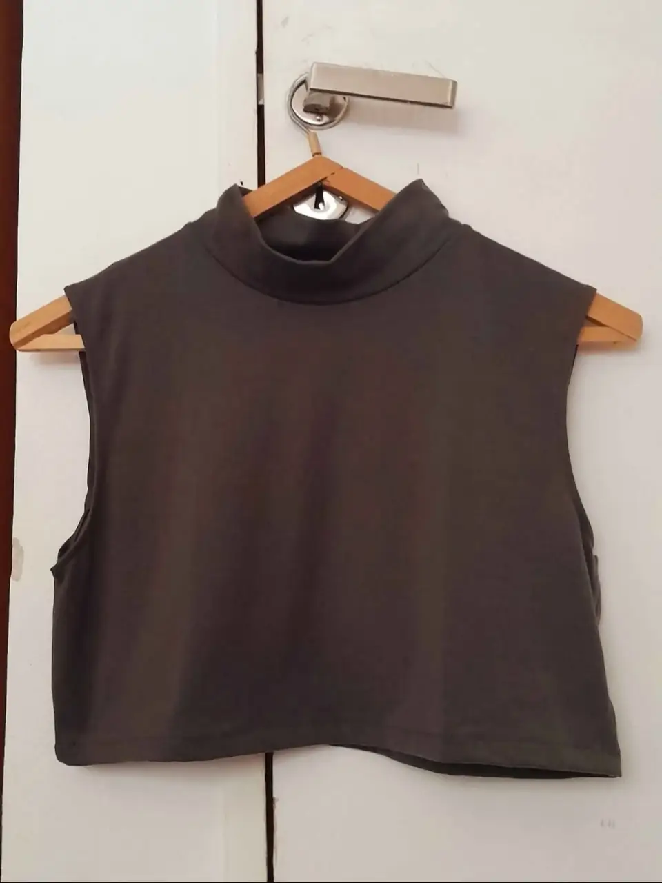 Top sin mangas de cuello alto en color verde militar oscuro, ideal para un look moderno y versátil.