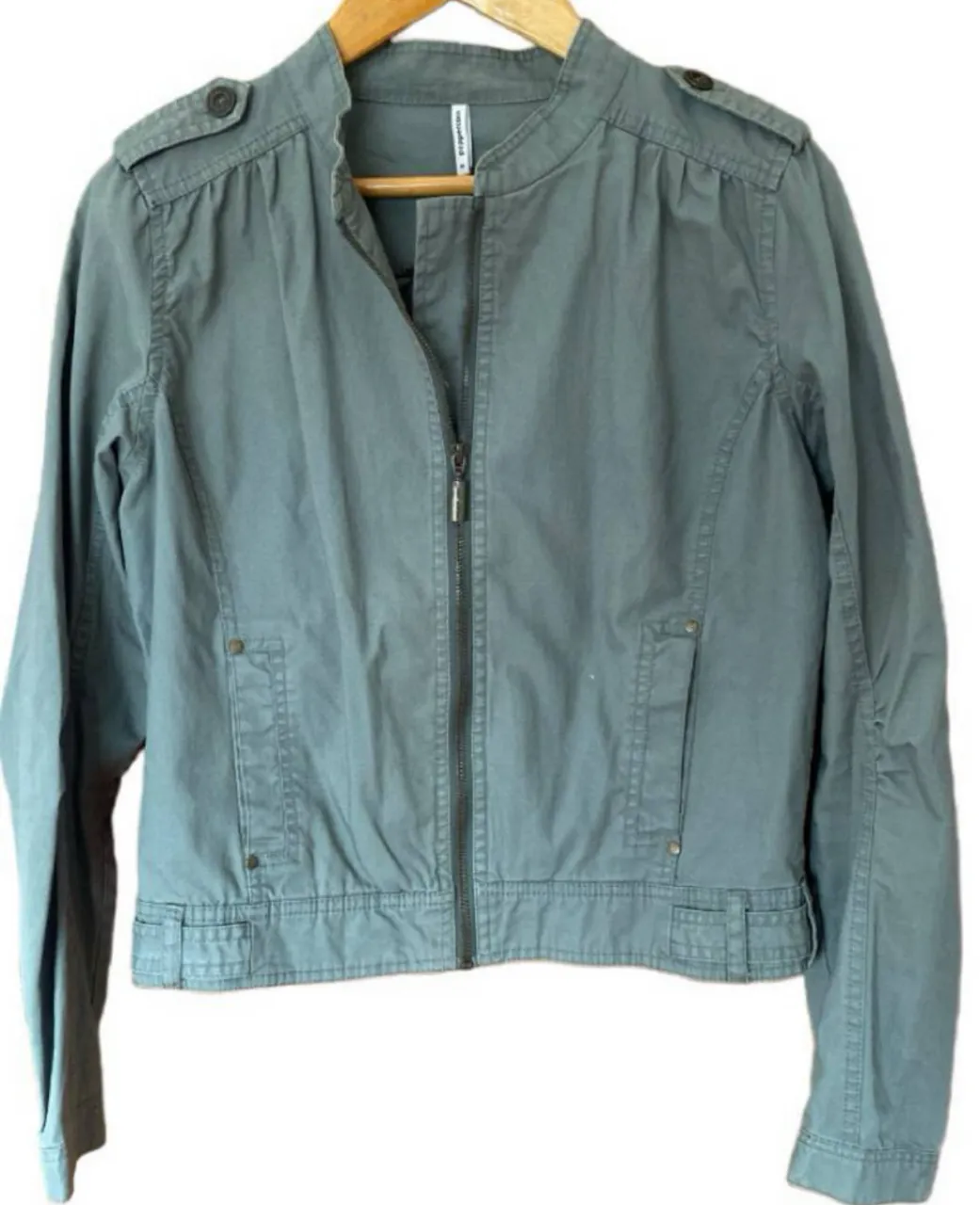 Campera bomber de mujer, color gris. Con cierre frontal, bolsillos y detalles en los hombros. Ideal para un look casual y moderno. De la marca Danesa Peppercorn. tiene unas Marquitas chiquitas  nada más 