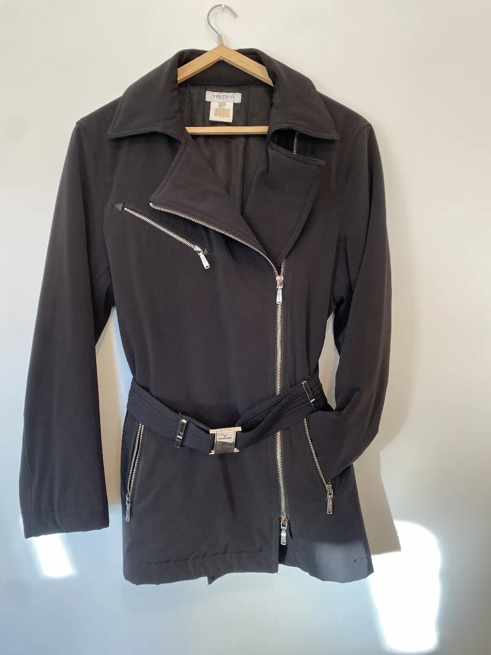 Espectacular cazadora impermeable negra estilo biker de la marca Vertigo Paris, con cierre asimétrico y cinturón. es gruesa y abriga. Ideal para un look moderno y versátil. Único detalle ese descosido en el forro de una de las axilas internas. Hombros 45, axilas 55, mangas 60, largo 75. 