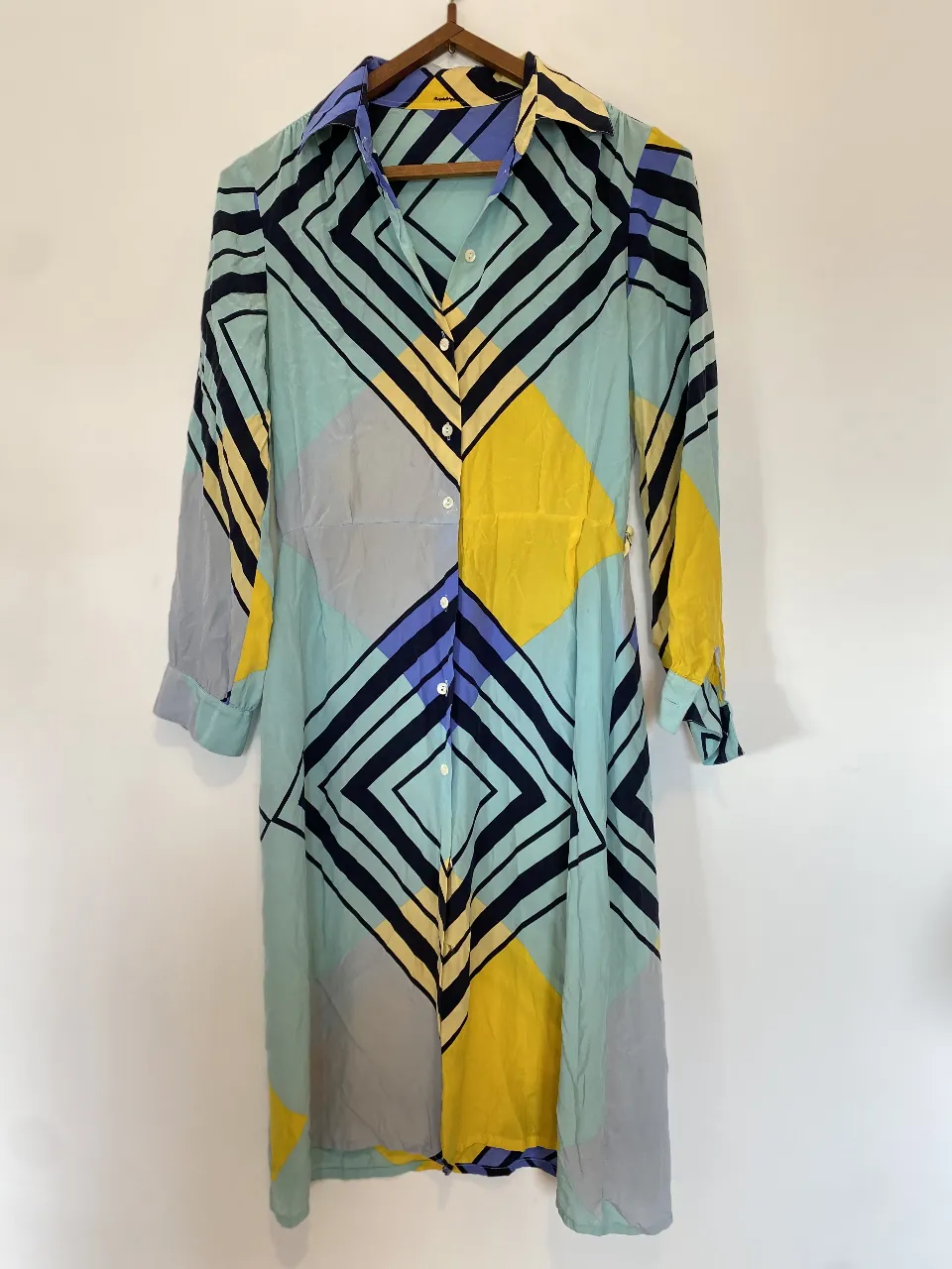 Vestido camisero con estampado geométrico en tonos celeste, amarillo y azul marino. Corte clásico con cuello camisero y mangas largas. Ideal para un look elegante y moderno. tiene las presillas para un cinturón (que perdí)
Hombros 39, axilas 44, manga 56, largo 105 