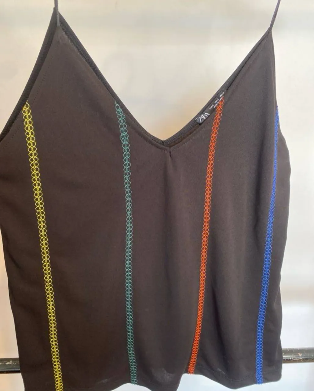 Musculosa negra con tiras finas y escote en V. Detalles de costuras en colores vibrantes. Ideal para un look casual y moderno.
