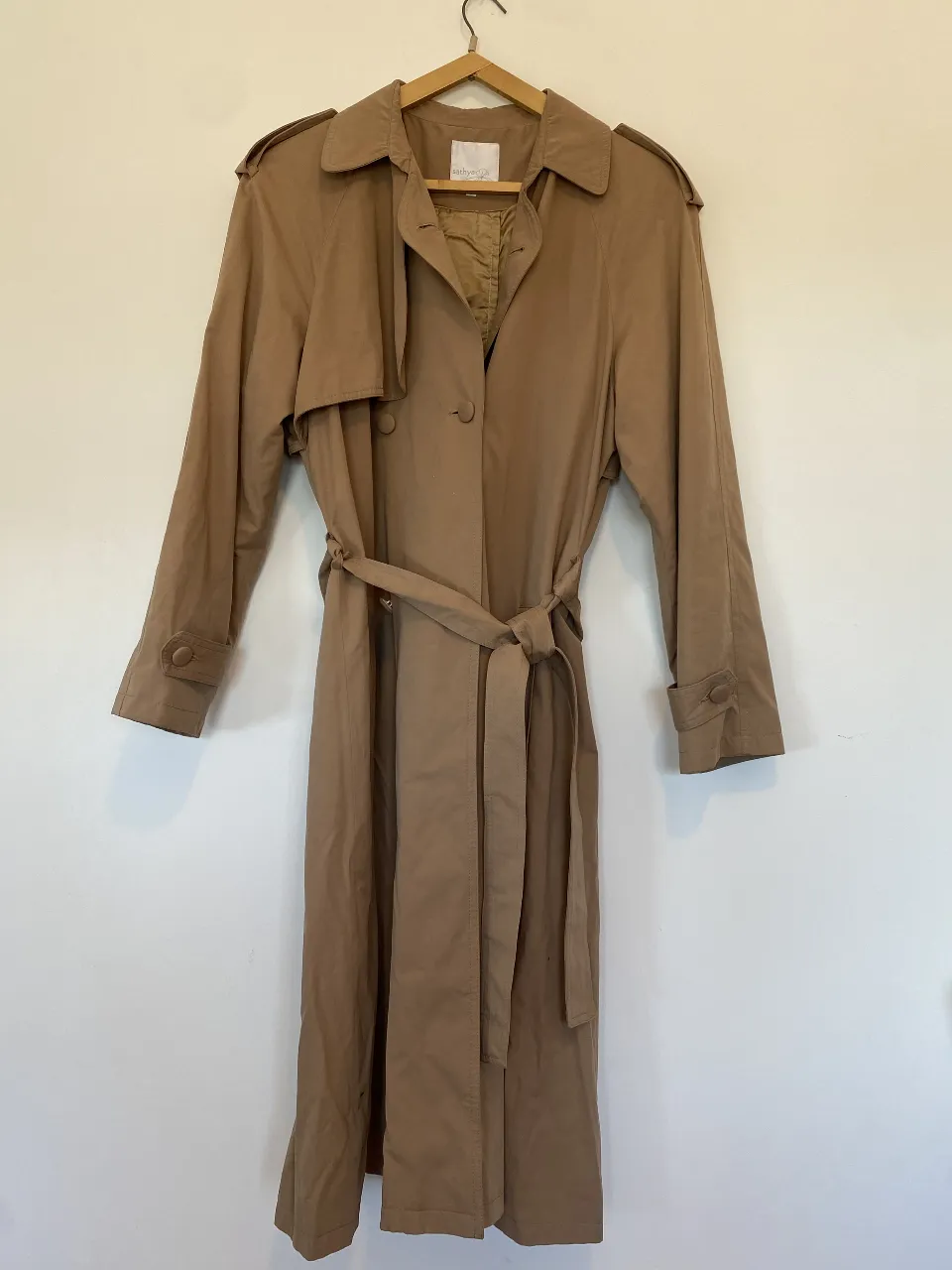 Trench coat largo color marrón, con cinturón para ajustar en la cintura. Posee solapas y botones forrados. Ideal para un look elegante y sofisticado. 