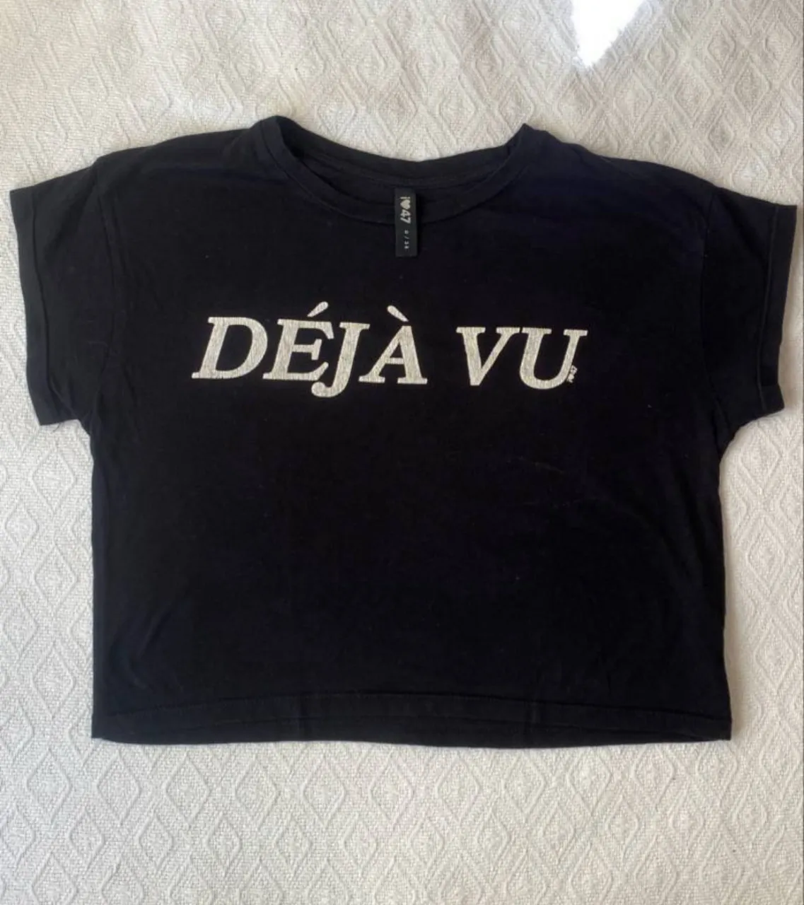 Remera negra de algodón con estampado "DÉJÀ VU" en blanco. Corte crop, ideal para un look casual y moderno.
