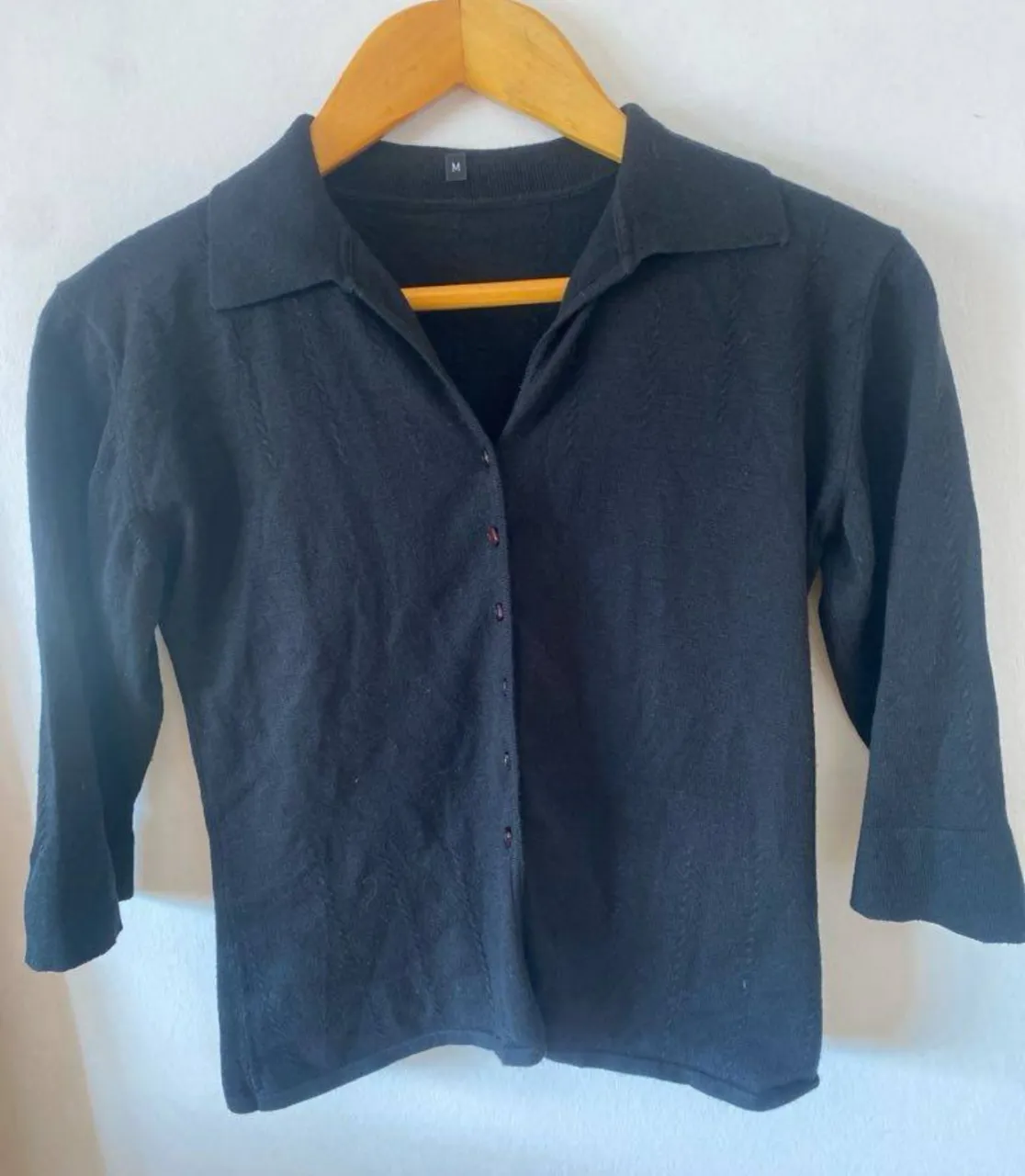 Sweater negro de manga 3/4 con cuello solapa. Ideal para un look elegante y versátil.