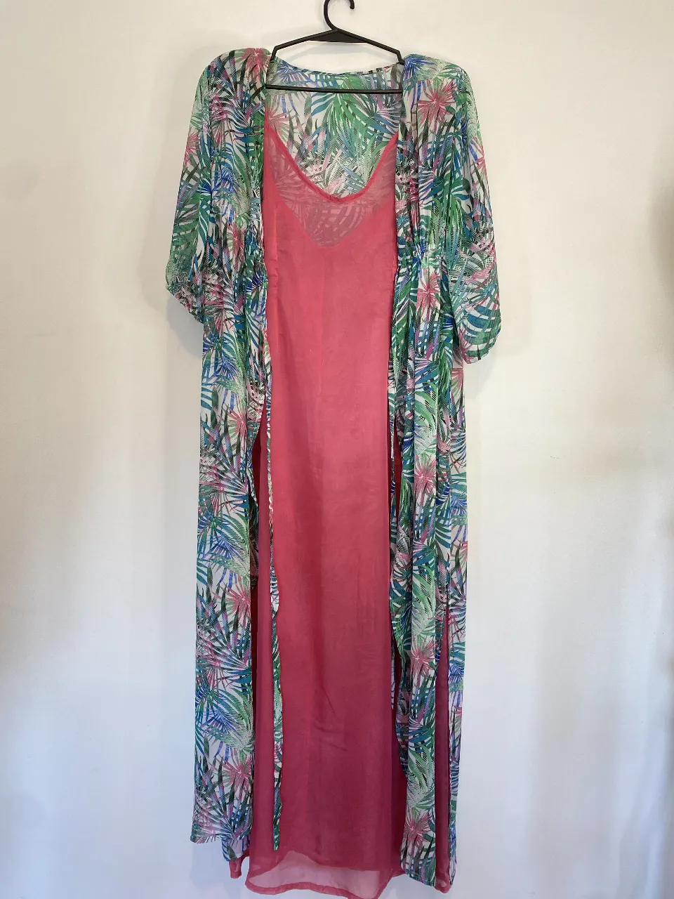 Kimono largo de gasa con hombreras con estampado de hojas tropicales en tonos verdes, azules y rosas. Incluye un vestido interior rosa liso. Ideal para un look fresco y veraniego. Único detalle se ve en una de las fotos el vestido interior desgastado en el escote . Axilas del vestido 49, largo total 145