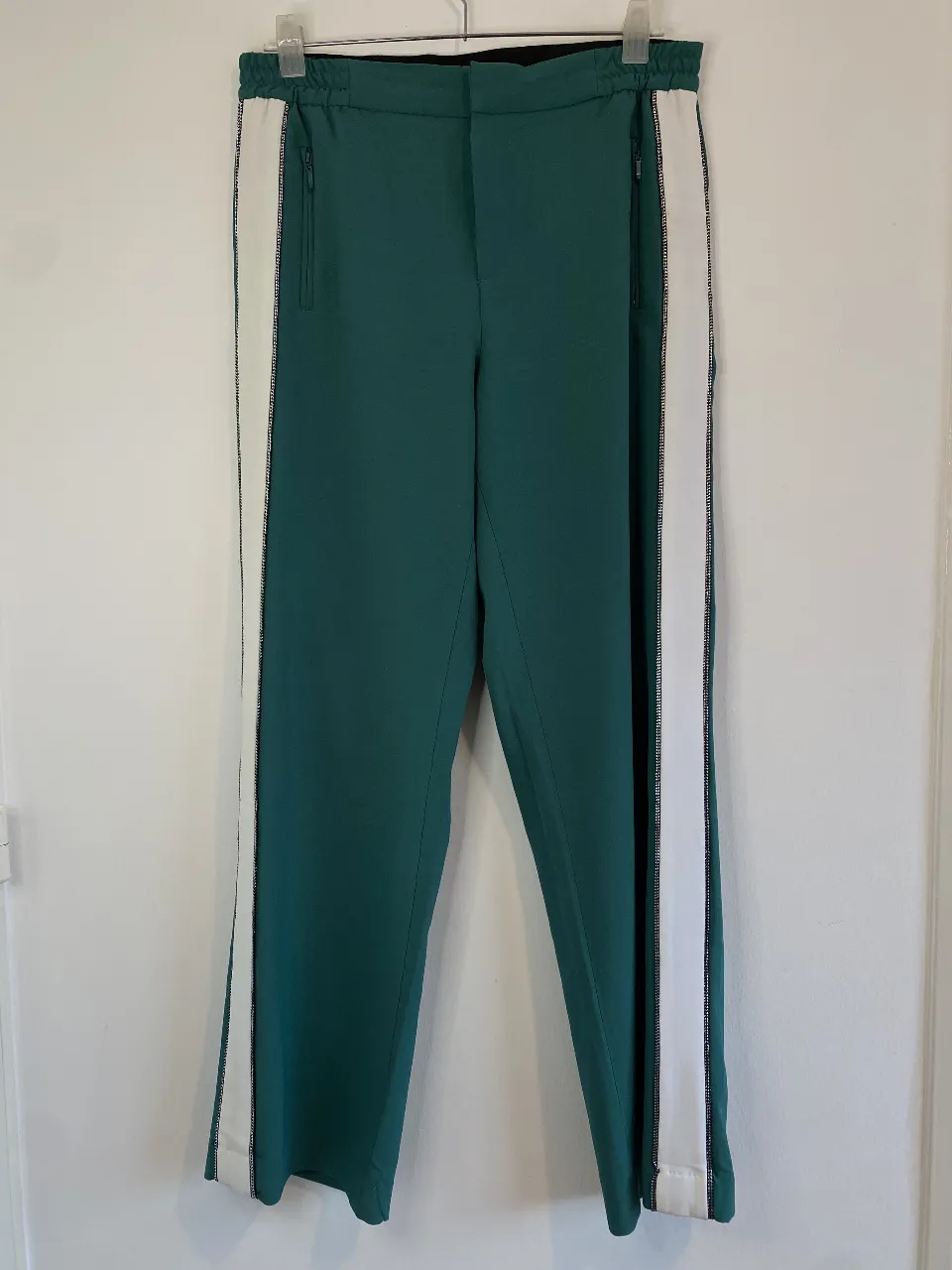 Pantalón sastrero verde con detalles blancos en los laterales. Tiene bolsillos con cierre y cintura elastizada. Marca Yagmour. Talle 50: cintura 42 (máximo 50) largo 108, tiro 31
El diseño de los laterales blancos estiliza muchísimo y queda Super lindo puesto