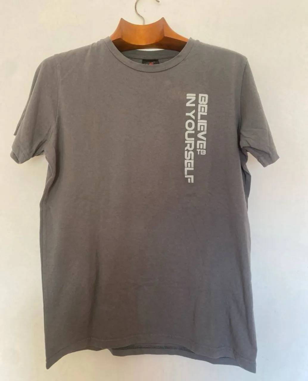 Remera gris con estampado vertical 'BELIEVE IN YOURSELF'. Talle M. Ideal para un look casual y cómodo.