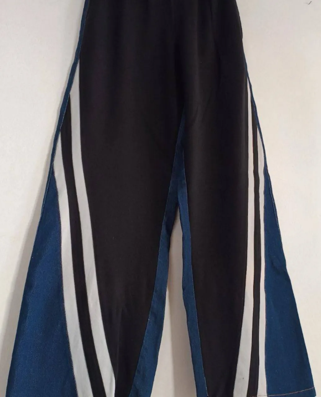 Pantalón de vestir negro con detalles en denim azul y franjas blancas laterales. Corte holgado y moderno, ideal para un look casual y con estilo. talle m hasta xl aprox ver medidas 
32 cm sin estirar y va hasta
45 cm comodamente y de caderas 56 cm sin estirar
tiene la etiqueta recortada y algunos detalles de uso
