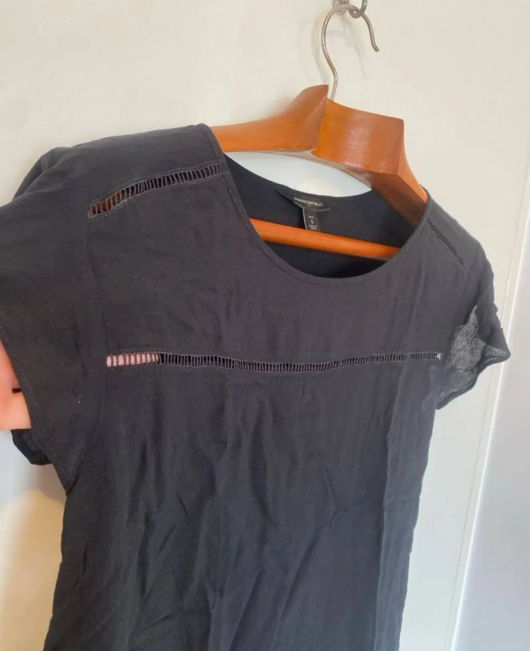 Blusa negra de la marca Banana Republic, con detalles calados en el frente y mangas cortas. Ideal para un look casual y elegante.