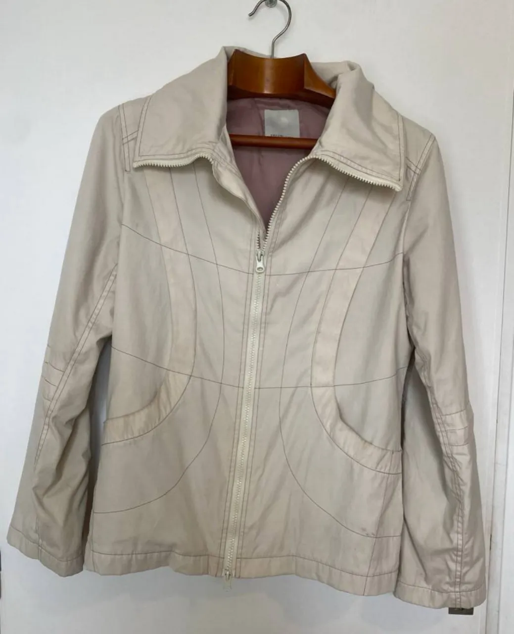 Campera de mujer color crudo, con cierre de doble deslizador y bolsillos. Diseño con costuras en contraste y cuello alto. Talle M. marca danesa oxmo