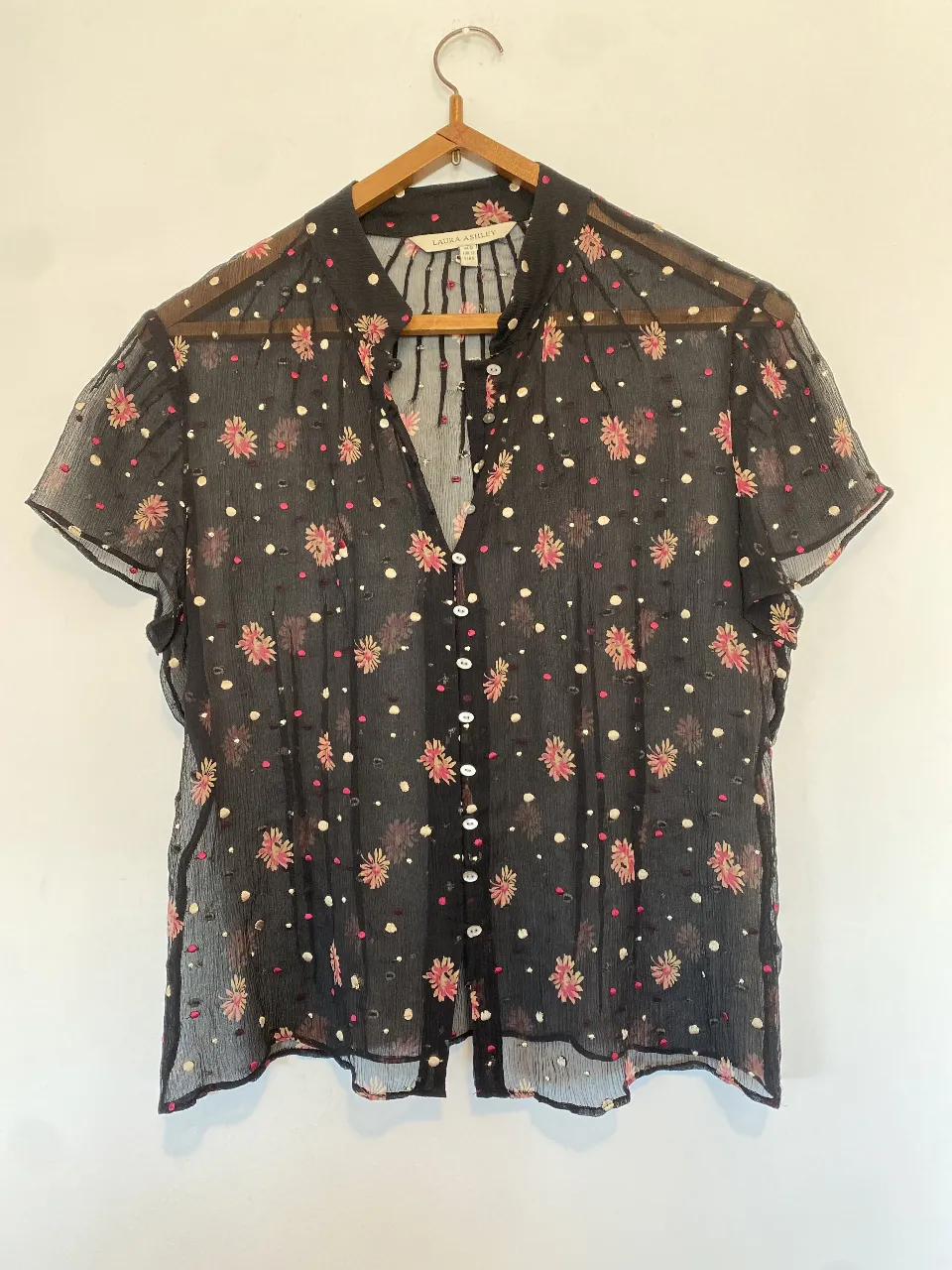 Blusa de gasa negra con estampado floral en tonos rosa y blanco. Cuello mao y botones delanteros. Ideal para un look elegante y femenino.
Axilas 46, largo 55