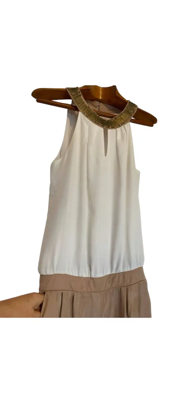 Mono largo de mujer, elegante y sofisticado. La parte superior es blanca con detalles dorados en el cuello, mientras que la parte inferior es de color marrón claro con cintura elastizada detrás. Ideal para eventos especiales o salidas nocturnas. le faltan algunas lentejuelas x eso el precio.