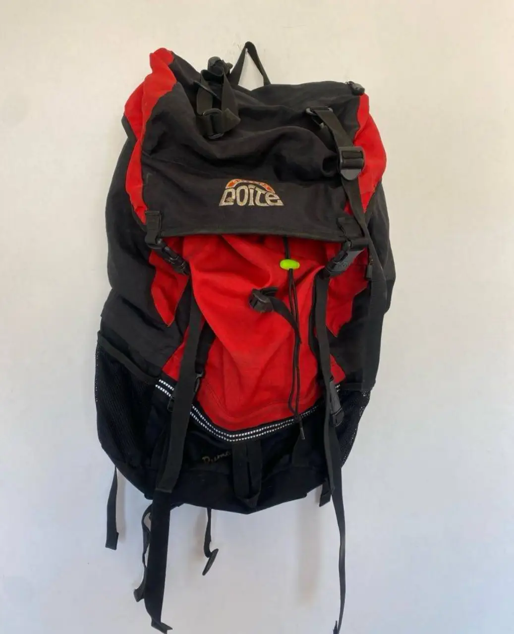 Mochila Doite roja y negra, ideal para actividades al aire libre. Cuenta con múltiples compartimentos y correas ajustables para mayor comodidad y tela antidesgarro.