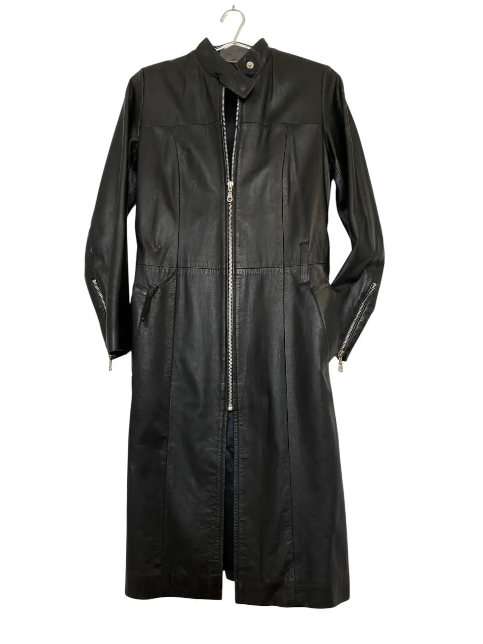 Espectacular trench largo de cuero negro, con cierre frontal y detalles de diseño. Ideal para un look moderno y sofisticado. Tiene el detalle que se ve en la ultima foto. 100% cuero BONN.  Hombros 37, axilas 45, mangas 60, largo 103, cintura a la altura de las presillas 41