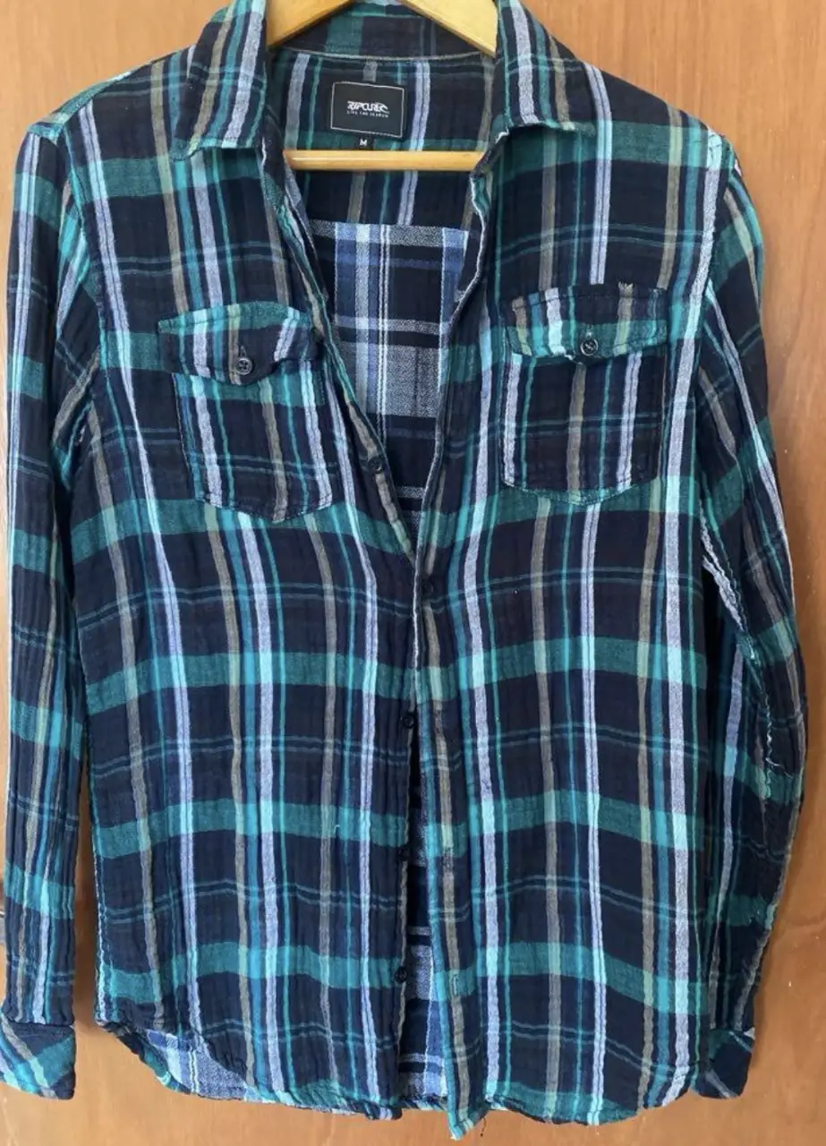 Camisa a cuadros Rip Curl de hombre, manga larga, con dos bolsillos delanteros. Talle M. Ideal para un look casual y canchero.