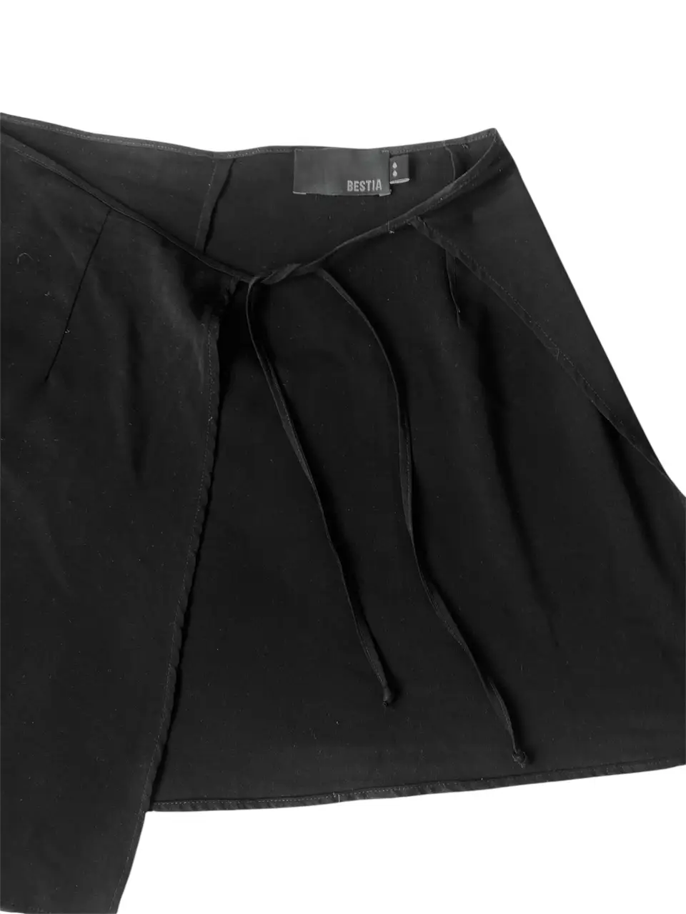 Pollera asimétrica negra con detalle de lazo en la cintura. Ideal para un look moderno y sofisticado. la tela es rayón 