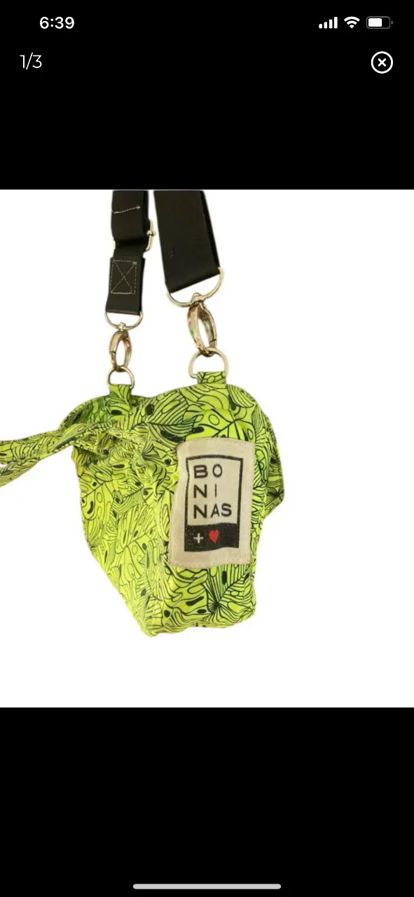 Bolso bandolera con estampado de hojas en color verde neón. Cuenta con manijas cortas y correa larga ajustable. Ideal para llevar tus esenciales con estilo y un toque de originalidad. 16x19cm