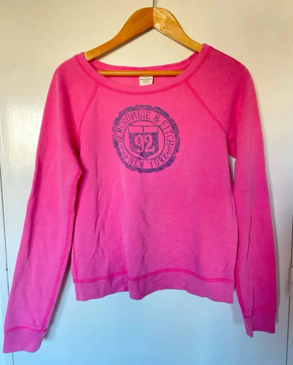 Buzo de cuello redondo rosa de la marca Abercrombie & Fitch, con estampado en el frente. Talle M. Ideal para un look casual y cómodo. Único detalle es esa manchita en la última foto