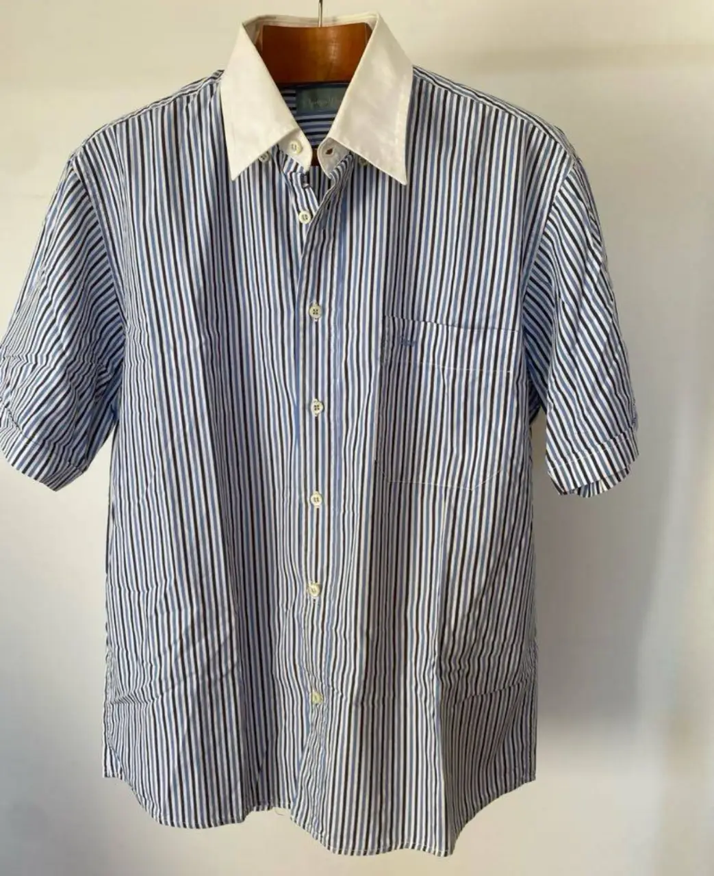 Camisa de hombre a rayas verticales en azul y blanco, con cuello blanco y mangas cortas. Ideal para un look casual y fresco.