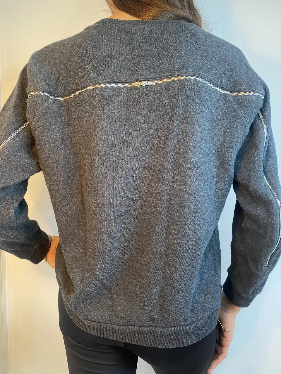 Sweater gris con cierre en la espalda y mangas. Ideal para un look casual y moderno.