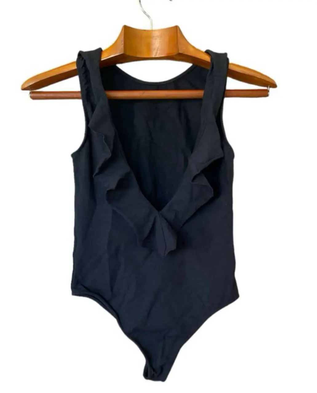 Body negro con volados en el frente, ideal para un look elegante y moderno. Confeccionado en una mezcla de viscosa y elastano, ofrece comodidad y ajuste perfecto. Perfecto para combinar con jeans o faldas. 